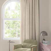 Fen&ecirc;tre avec rideau &agrave; fleurs color&eacute;es en rouge, orange et bleu, fauteuil vert et petite table avec lampe